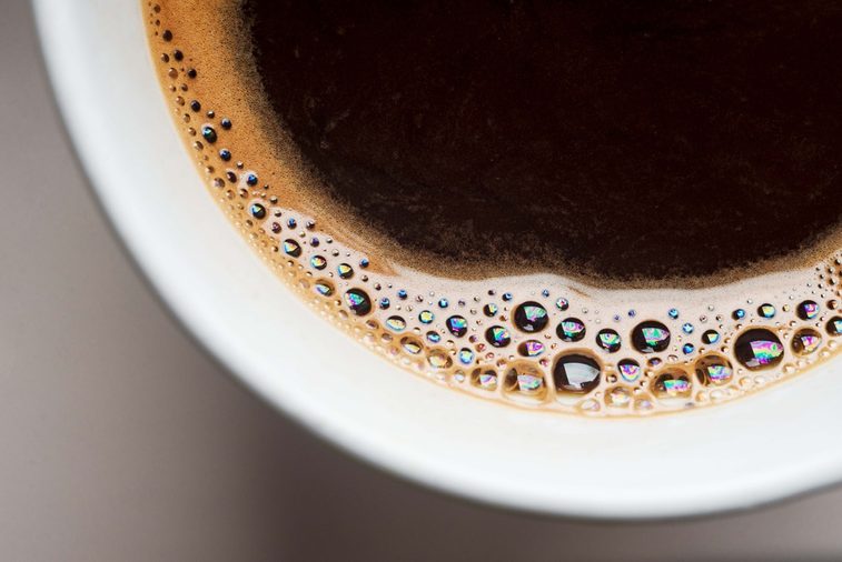 white cup of black coffee from above. top view of coffee bubble close up. caffeine bubble isolated.