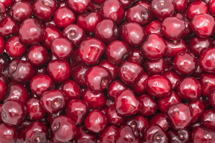 Beautiful texture of fresh cherry fruits. Prunus avium. Red fruity background. Pile of sweet ripe cherries full of vitamins, antioxidants and a delicious juice. Tasty and healthy vegetarian dessert.