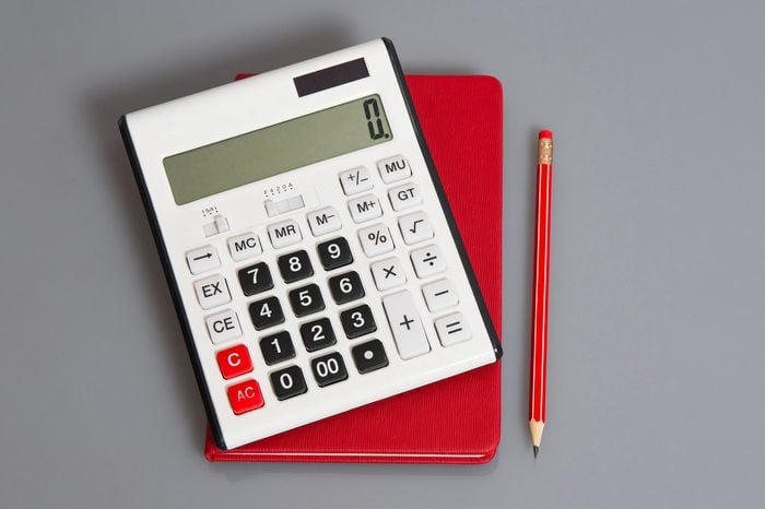 calculator, red notebook, and red pencil on gray background