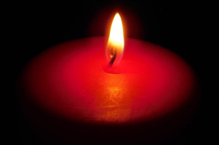 Single red candle in the darkness