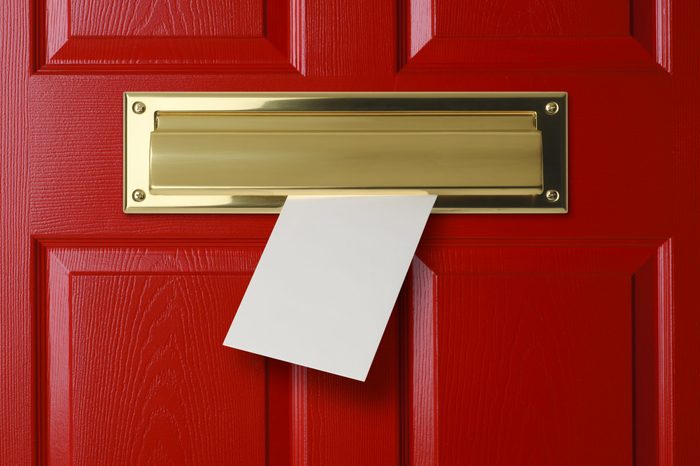 A letter coming through a gold mail slot in a red door.