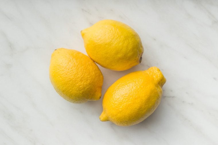 Three yellow lemons on table. Top view.