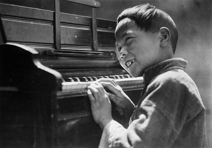 A happy Chinese boy practices his Easter Alleluias on the missionary's piano in Loyang , China.