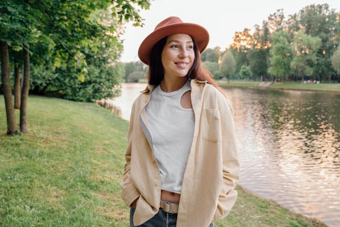 Relaxed Portrait of a girl in a hat standing by a river