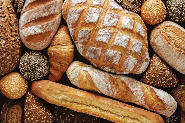 Bread background, top view of white, black and rye loaves on black