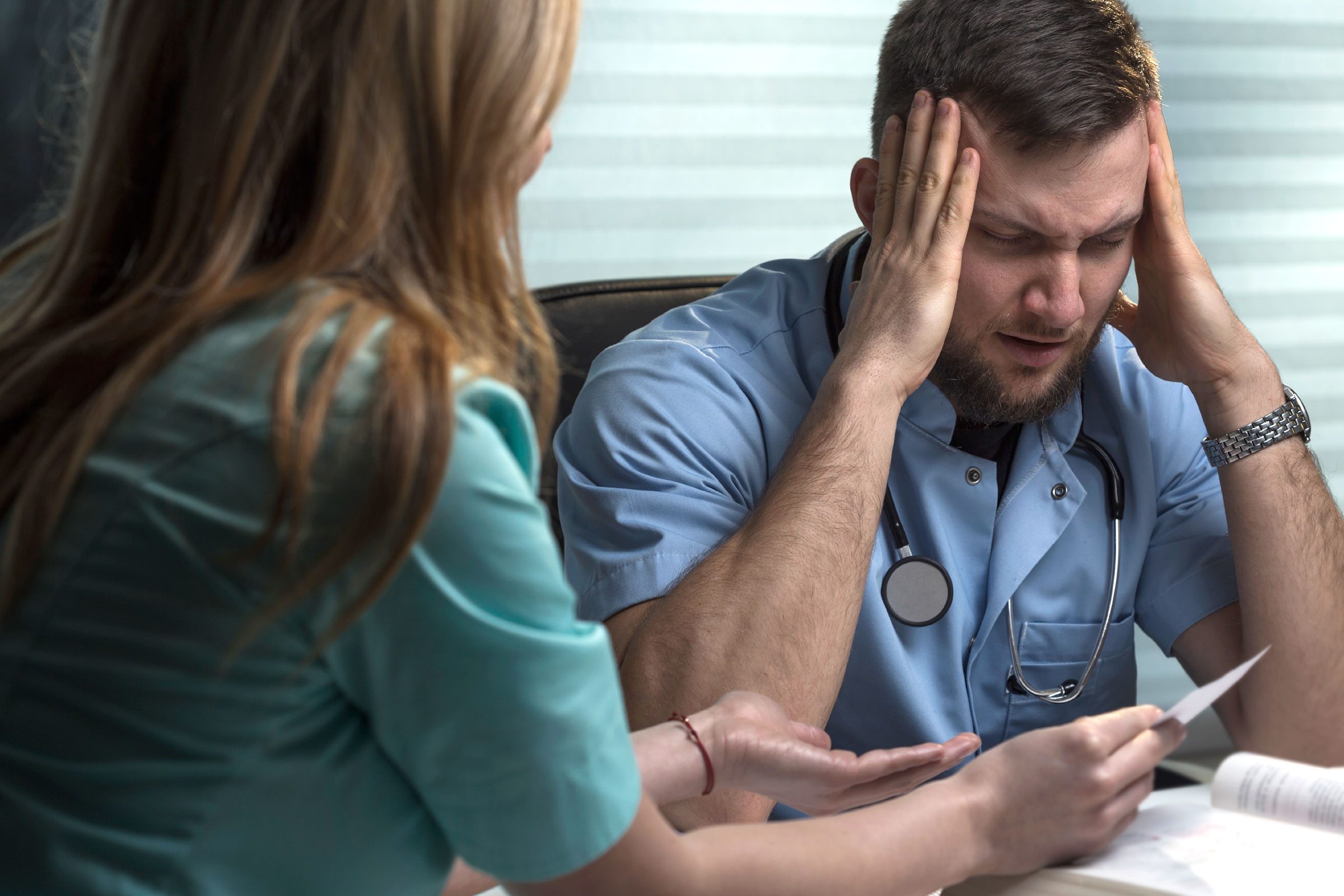 stressed healthcare worker holding head