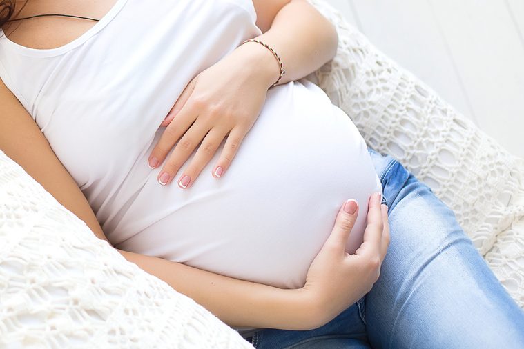 Closeup pregnant woman belly at white background