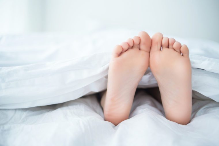 Person's foot in bed