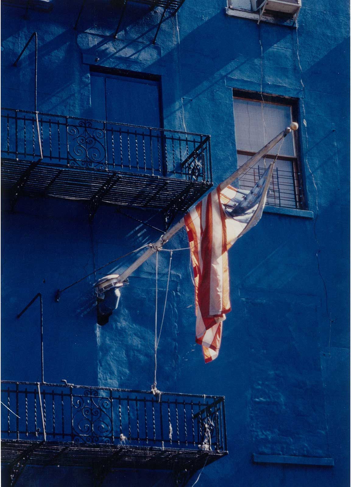 light shines on a faded hanging hanging on a pole on the side of a blue building