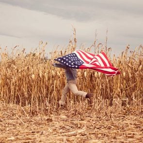 a retired Marine runs across his family’s cornfield in Harrisonburg, Virginia holding an american flag above his head