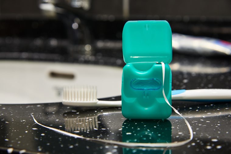 Dental floss with opened lid on a background of washstand