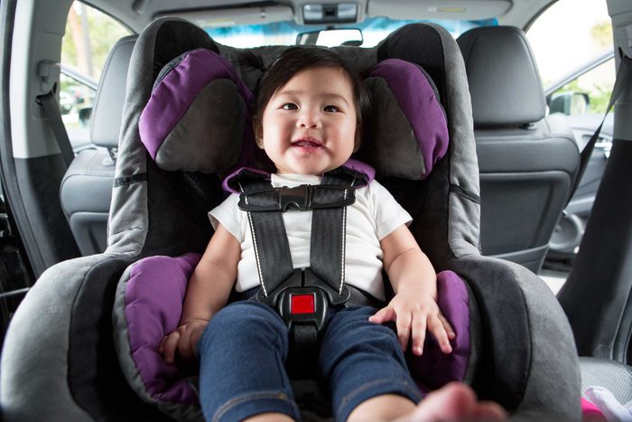 happy child in a rear facing car seat in the back seat of a car