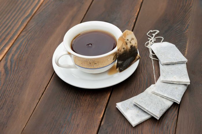 cup of tea with extra tea bags arranged on a wood table