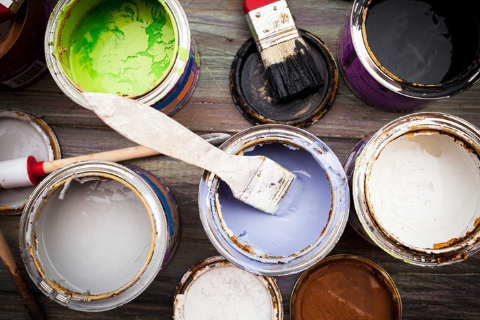 overhead view of open cans of paint with paint brushes