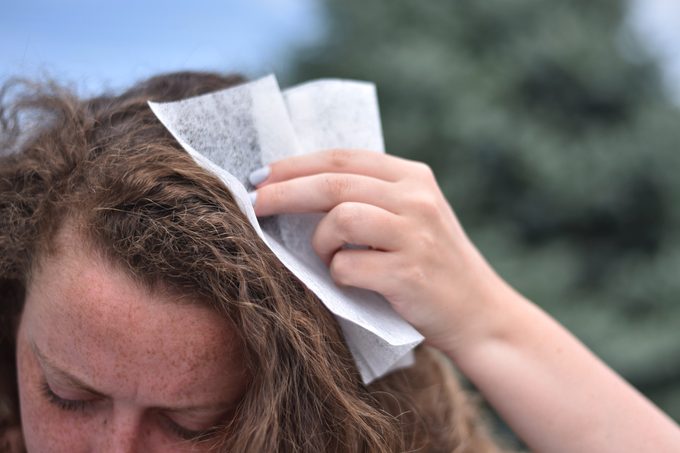 woman wiping her hair with a dryer sheet