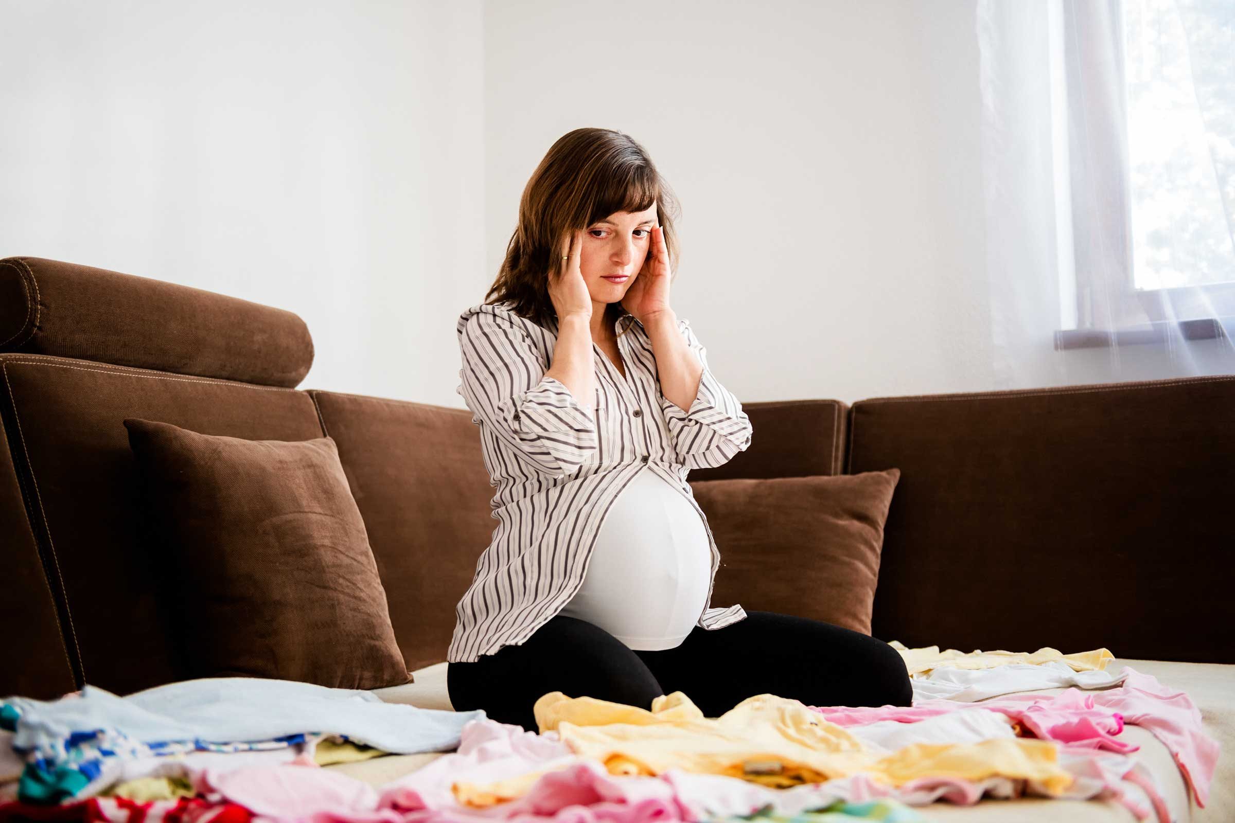 pregnant woman sitting on floor with laundry