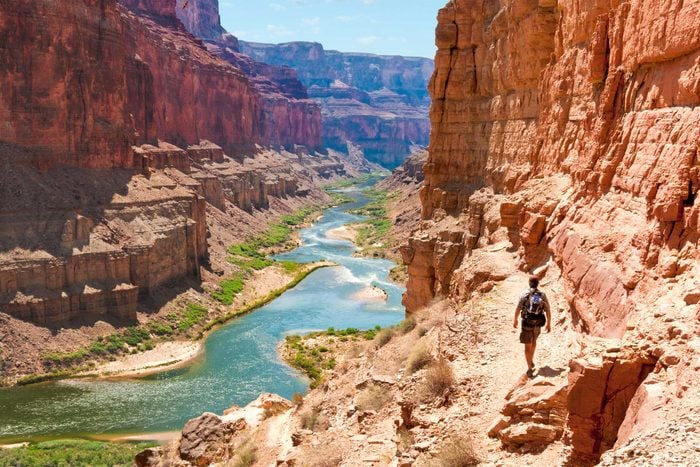 man hiking the Grand Canyon in Arizona with a view of the Colorado river below