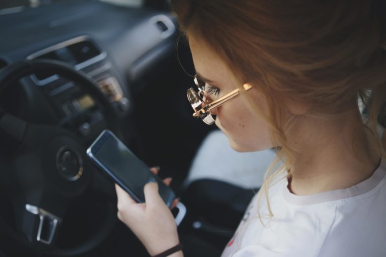 Attractive Blonde Woman Text Messaging on Her Cell Phone While Driving.