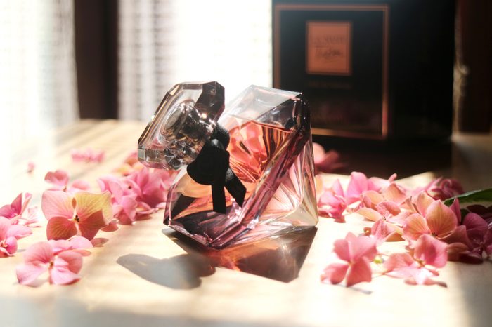 Paris, France: August 18 2018- A bottle of Lancôme La nuit Trésor perfume with ิblowing light and shadow, with petals of pink flowers