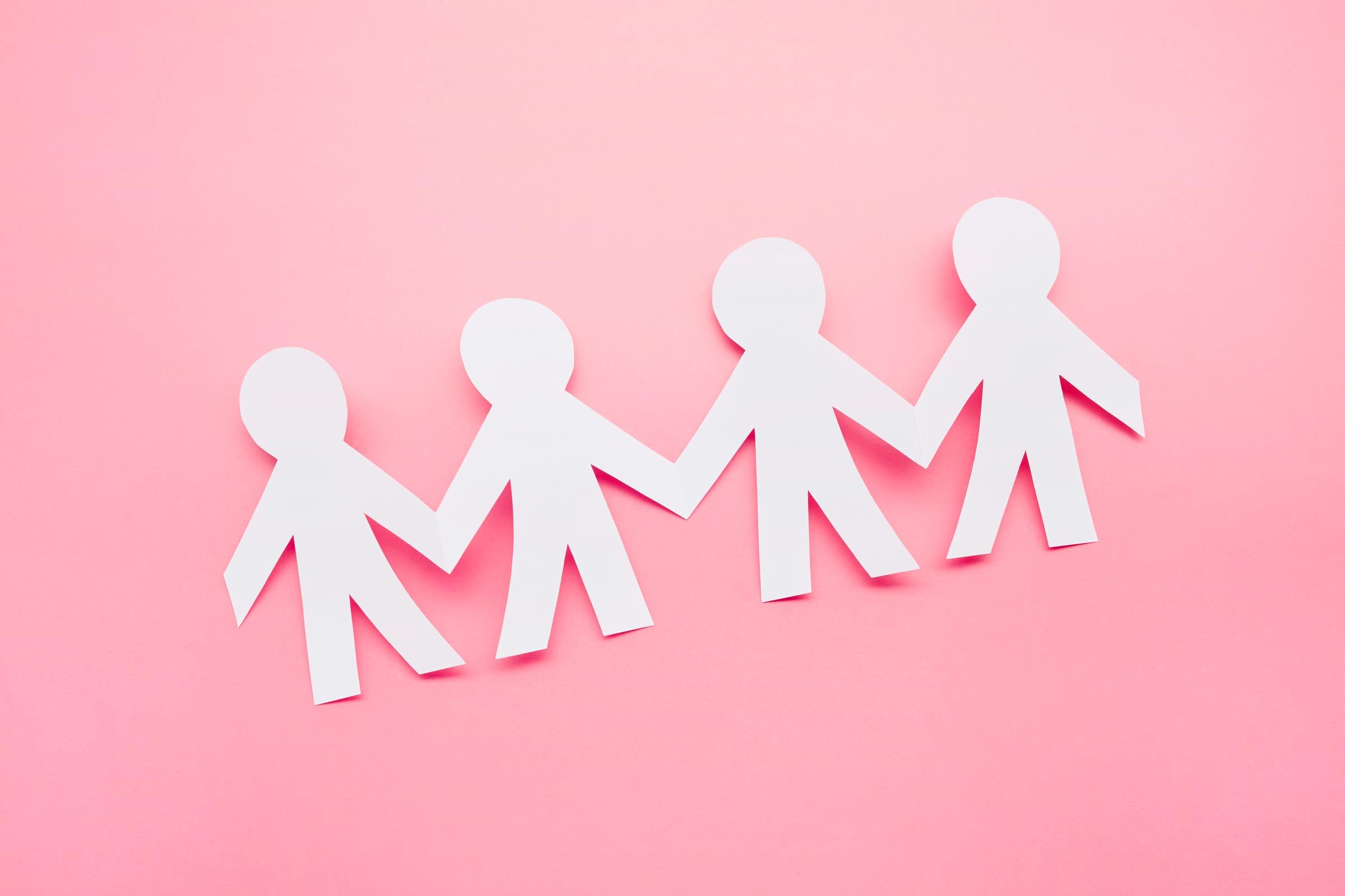 High angle view of paper people on pink background