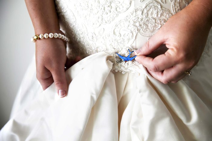 anonymous bride positioning a small blue pin onto her dress