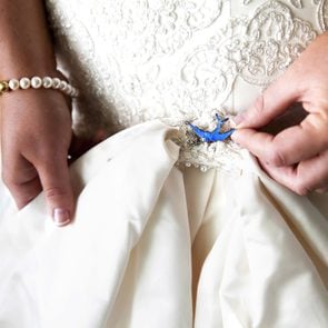 anonymous bride positioning a small blue pin onto her dress