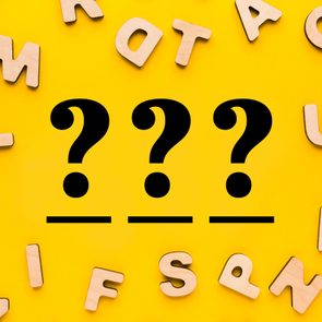 scattered wooden letters on a yellow background with three question marks over three blanks in the center