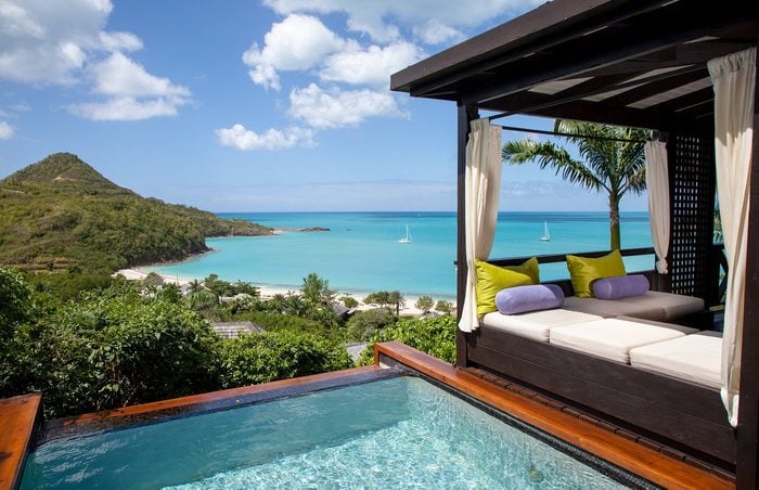 bed next to a pool with a view of the ocean at Hermitage Bay