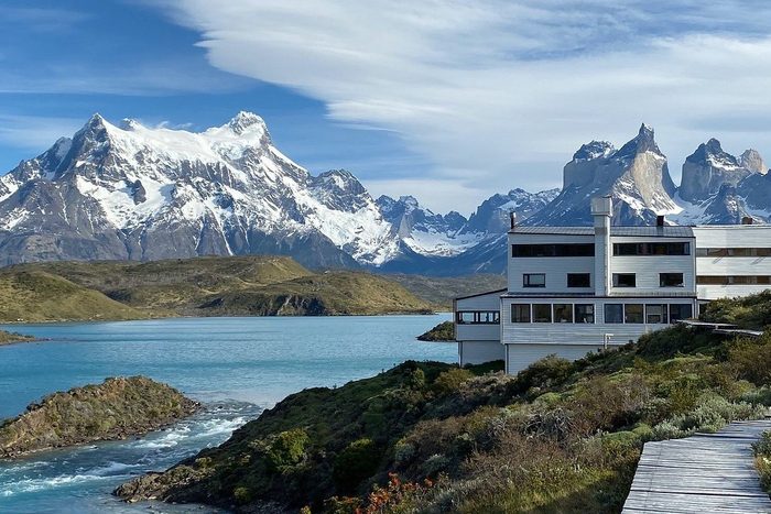 building next to a lake with large snowy mountains in the background at Torres Del Paine resort