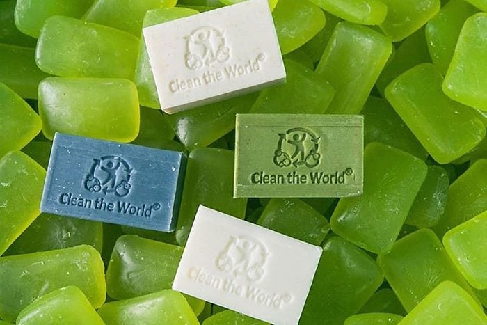 four bars of soap that say "clean the world" on a background of there unlabeled green bars of soap