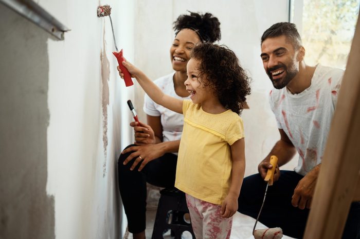 Young family renovating their home, painting wall