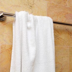 white bath towel hanging on a towel rod in the bathroom