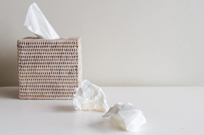 Rattan tissue box and crumpled tissues on table - cold and flu season concept, grief, concept (selective focus)