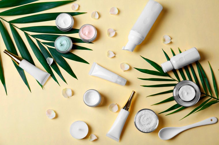 a collection of skin products on a yellow surface with palm leaves