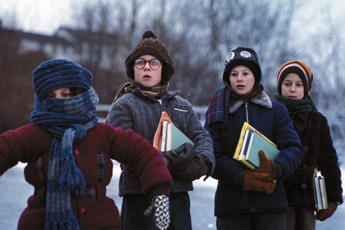A scene from A Christmas Story with a group of 4 boys dressed for winter walk to school carrying books