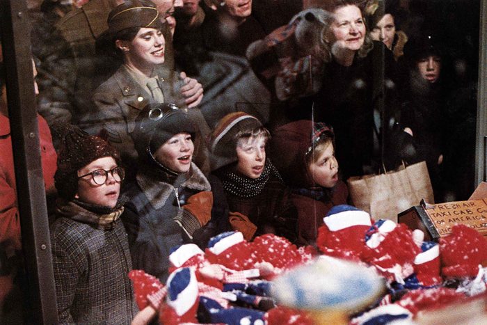 A scene from A Christmas Story with a group of people with excited looks on their faces look into a store window at something unseen