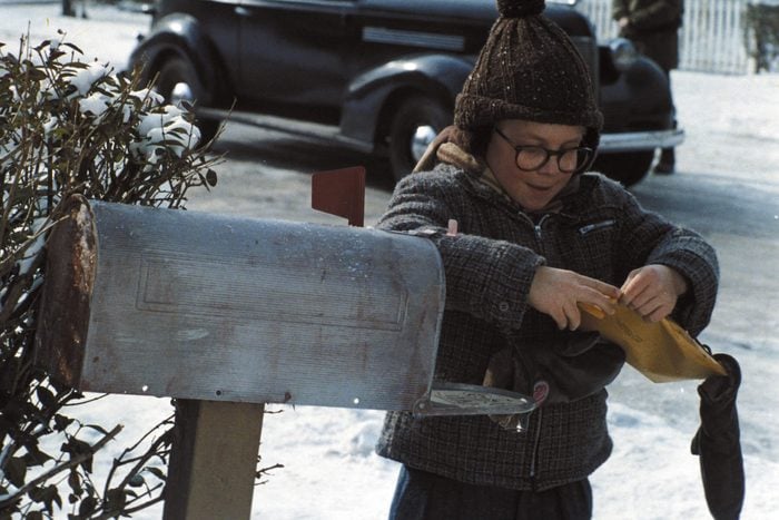 A scene from A Christmas Story with a boy outside in winter clothes checking the mail