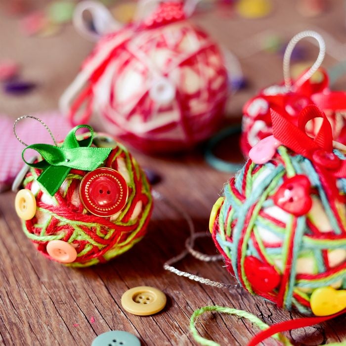closeup of some different handmade christmas balls, made with, cords, ribbons and buttons, on a rustic wooden surface
