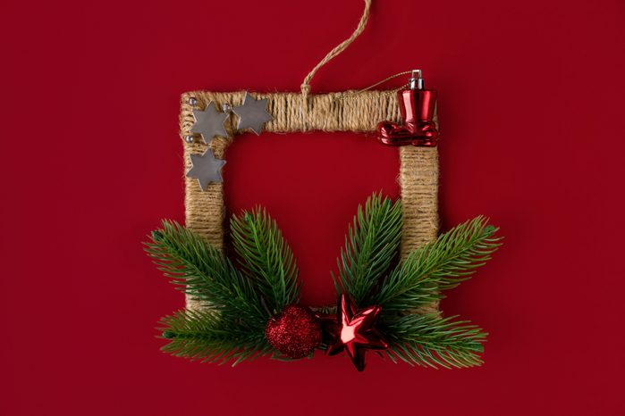 Frame of coniferous branches, Christmas toys, made by the hands of a child for the celebration of Christmas on a red background