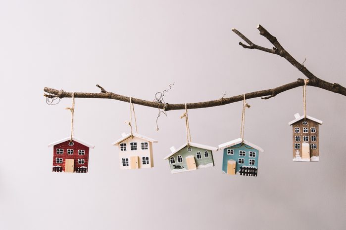 Beautiful festive new year and Christmas decorative little wooden houses hanging on a stick on the grey wall background
