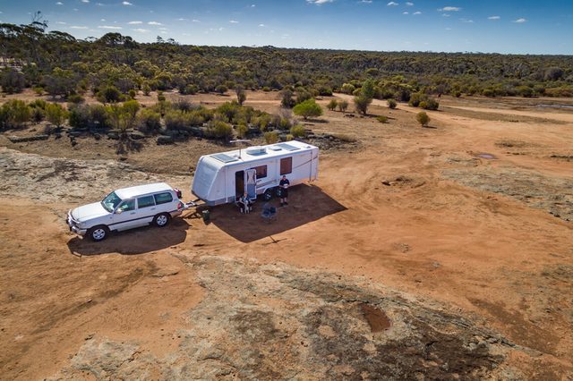 Aerial view of four wheel drive vehicle and caravan camped in the outback of Australia.