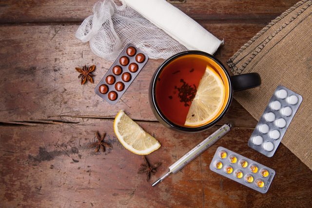 Seasonal flu: pills, thermometer and tea with lemon. View from above