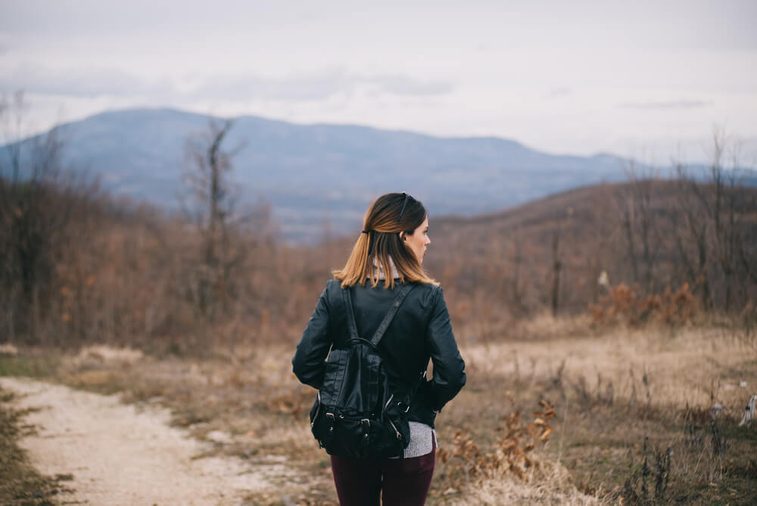 Girl with a black leather backpack exploring the nature.