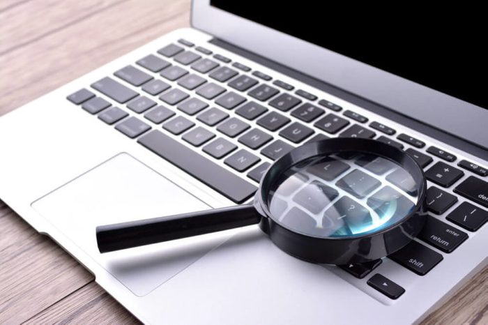 Laptop computer with magnifying glass, concept of search