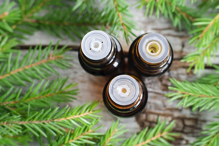 Three bottles of essential oil and fir branches. Christmas aromatherapy and spa concept. 