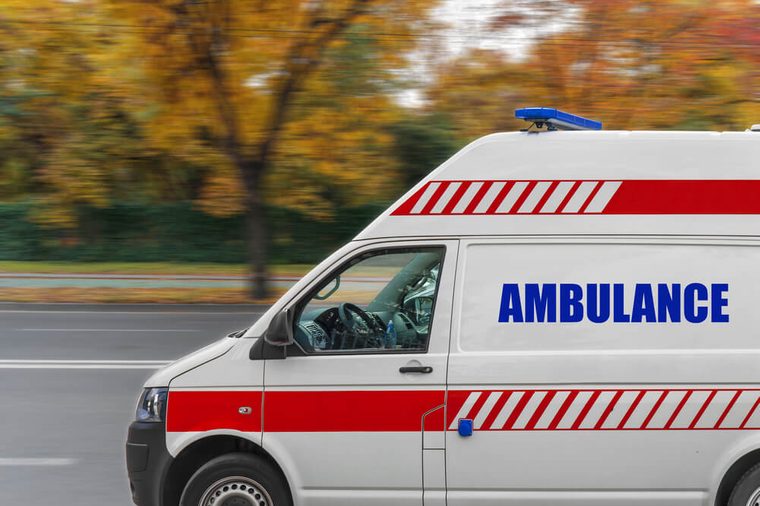 Ambulance service van driving fast on street 