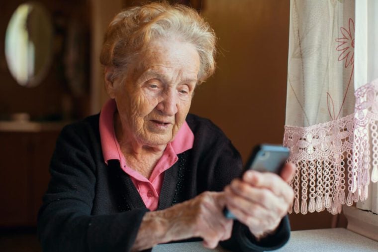 An old woman uses a smart phone.