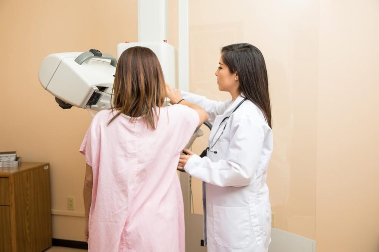 Female doctor and a patient standing in front of a breast tomosynthesis machine in a hospital