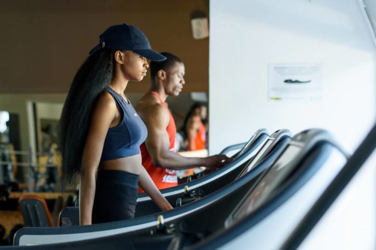 Black trainer and sexy african american woman on the treadmill in gym. Fitness concept