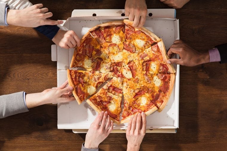 Group Of Hands Taking Each Slice Of Pizza From The Box